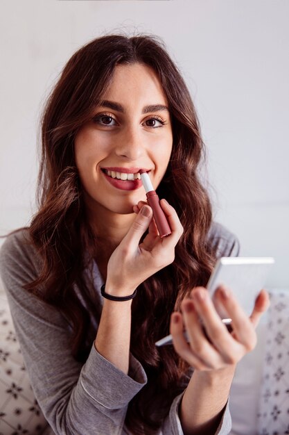 Femme souriante rouging lèvres