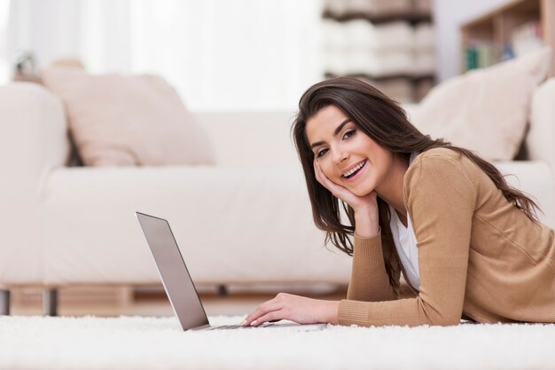 Femme souriante se détendre à la maison avec un ordinateur portable