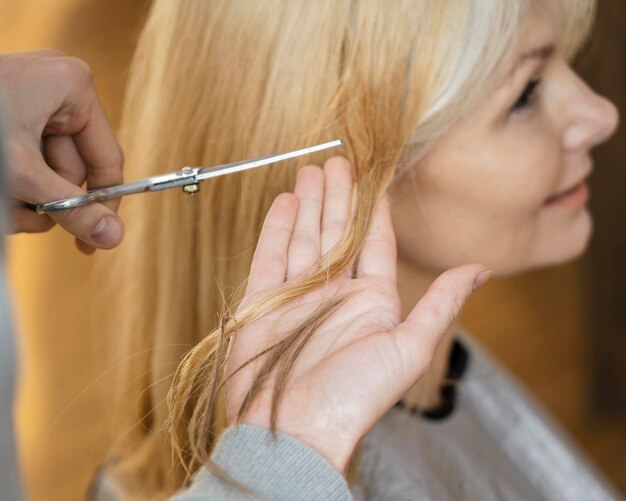 Femme souriante se faire couper les cheveux à la maison avec un coiffeur