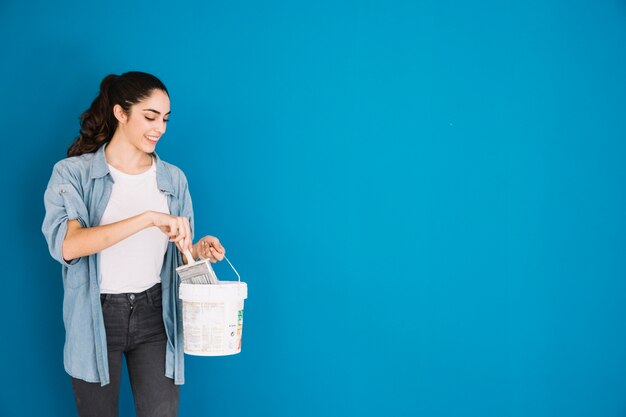 Femme souriante avec seau de peinture