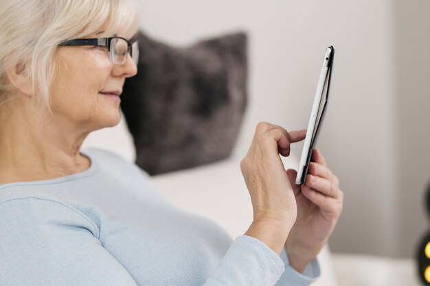 Femme souriante avec tablette sur le canapé