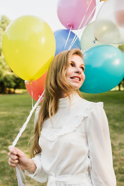 Femme souriante tenant des ballons en plein air
