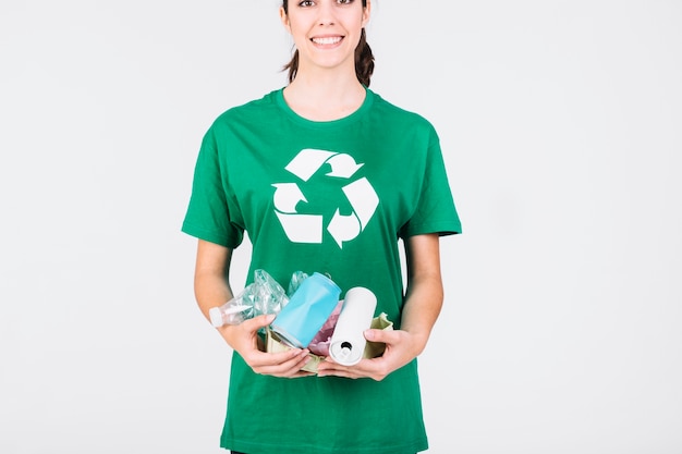 Femme souriante tenant des boîtes de conserve et des bouteilles en plastique