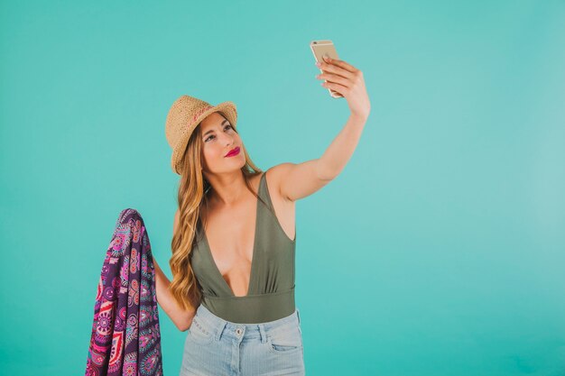 Femme souriante en tenue de plage prenant une selfie