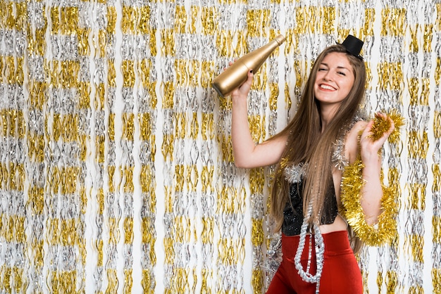 Femme souriante en tenue de soirée avec une bouteille de boisson