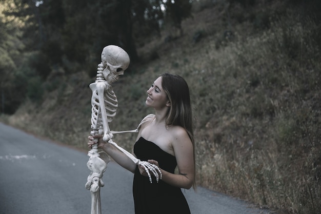 Photo gratuite femme souriante, tenue, squelette décoratif, debout, sur, route