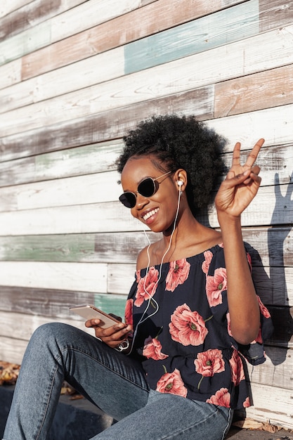 Femme souriante tir moyen faisant le signe de la paix