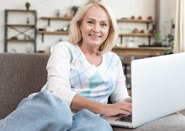 Femme souriante tir moyen avec ordinateur portable