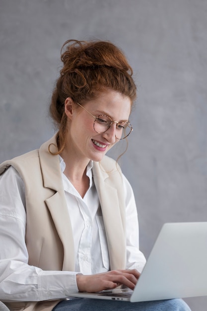 Femme souriante travaillant sur la vue latérale d'un ordinateur portable