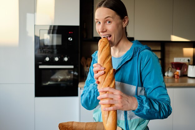 Femme souriante veut mordre une baguette