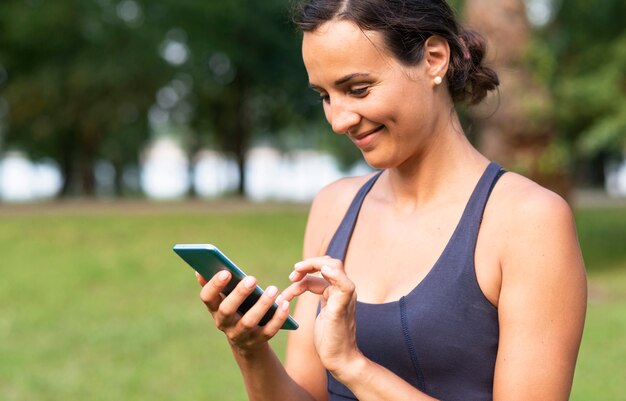 Femme souriante vue de côté avec smartphone