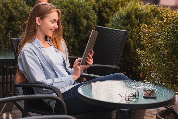 Femme souriante vue de côté avec tablette