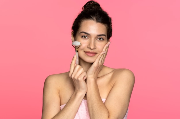 Femme souriante vue de face à l'aide d'un rouleau facial