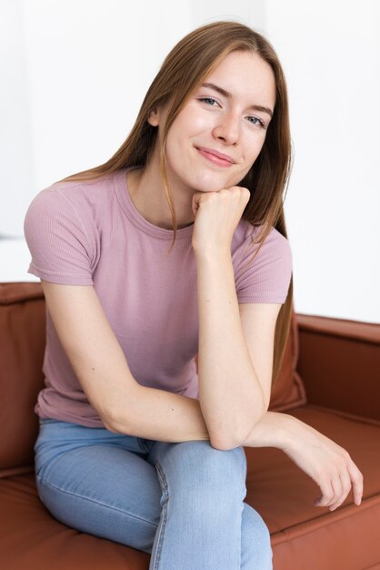 Femme souriante vue de face, assise sur le canapé