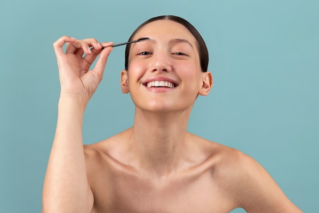 Femme souriante vue de face avec brosse à sourcils