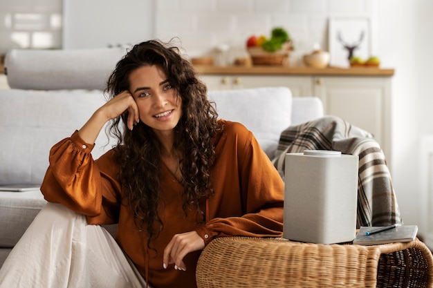 Femme souriante avec vue de face du haut-parleur intelligent