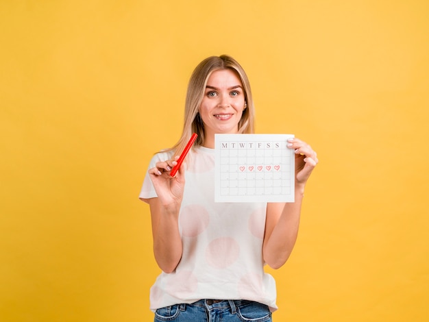 Femme souriante vue de face tenant le calendrier de la période