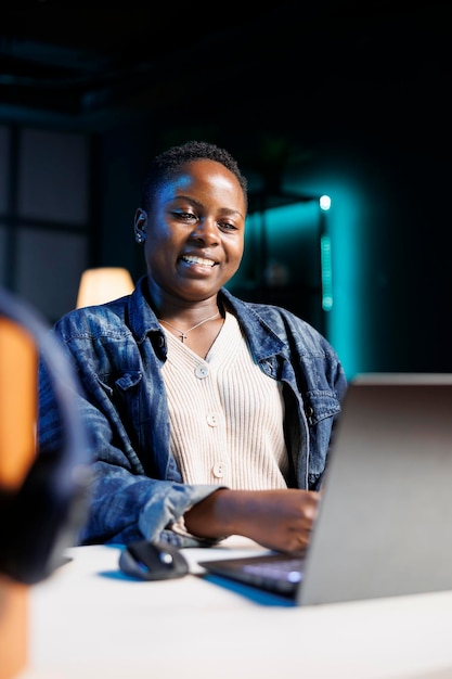 Une femme sourit en utilisant un ordinateur portable