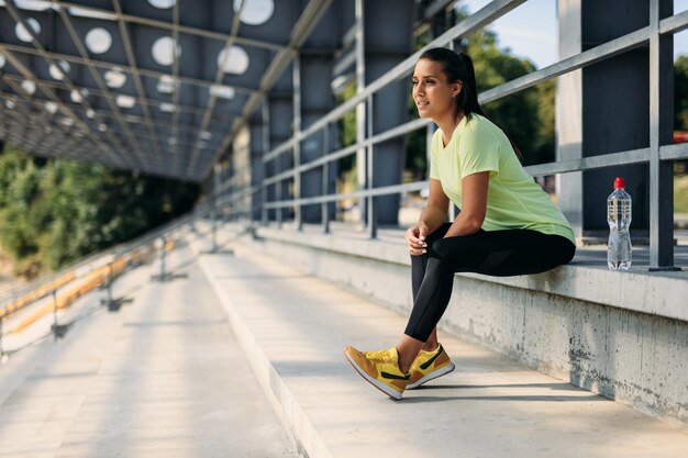 Femme sportive assise sur le stade avec une bouteille d'eau