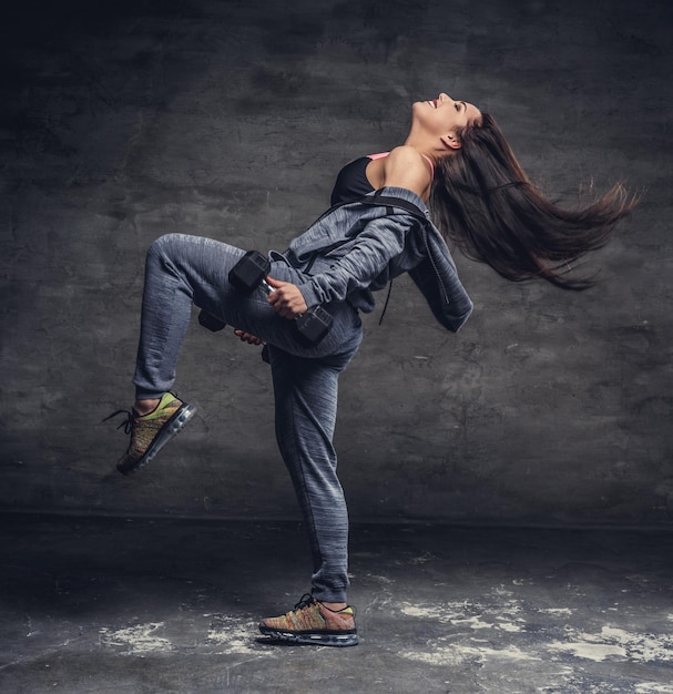 Femme sportive brune en action avec des haltères.