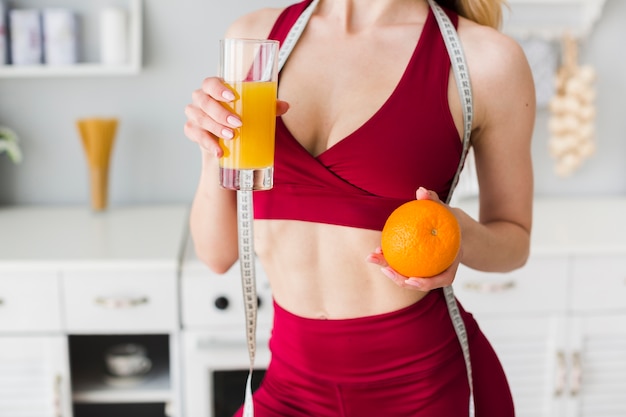 Photo gratuite femme sportive dans la cuisine avec du jus de fruits