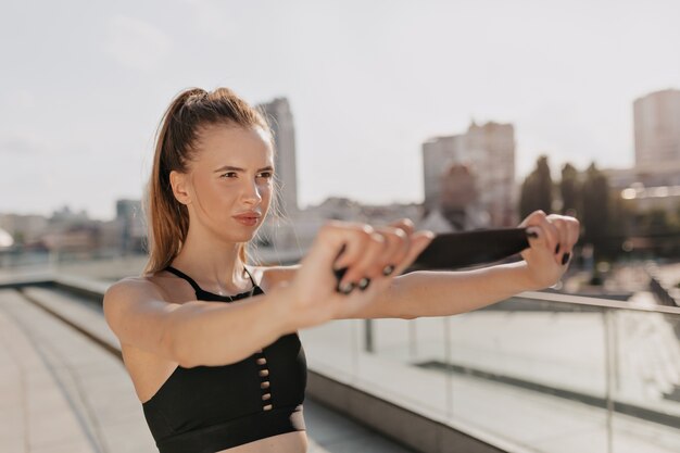 Femme sportive étirant ses bras et à la recherche concentrée en plein air dans la ville