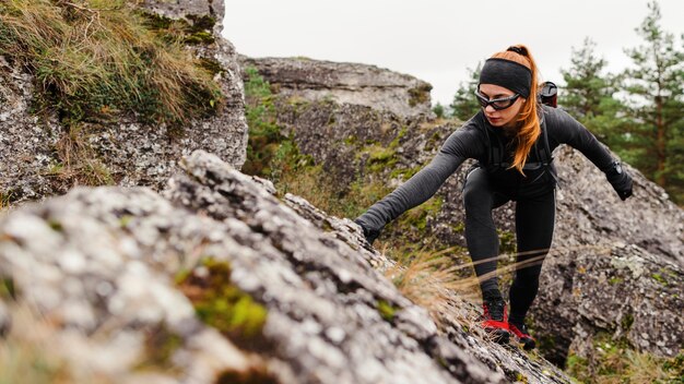 Femme sportive jogger escalade pierres vue de face