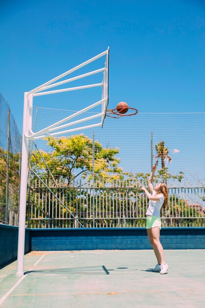 Femme sportive, lancer la balle dans le cerceau sur fond de nature