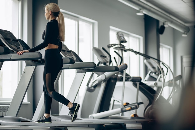 Femme sportive qui court sur tapis roulant à la salle de gym