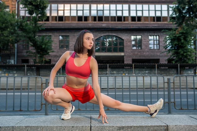 Photo gratuite femme sportive qui s'étire et se réchauffe les jambes avant de faire de l'exercice de fitness urbain. concept de sport et de mode de vie sain. athlète féminine exerçant à l'extérieur.