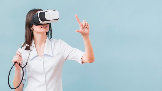 Femme avec stéthoscope à l'aide d'un casque de réalité virtuelle