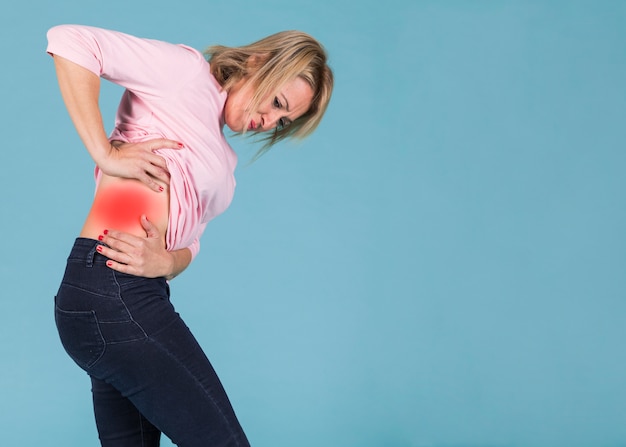 Femme stressante souffrant de douleurs lombaires sur fond bleu