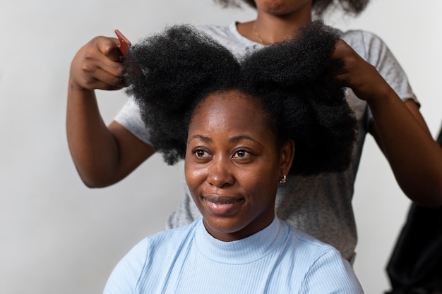 Photo gratuite femme styliste prenant soin des cheveux afro de son client