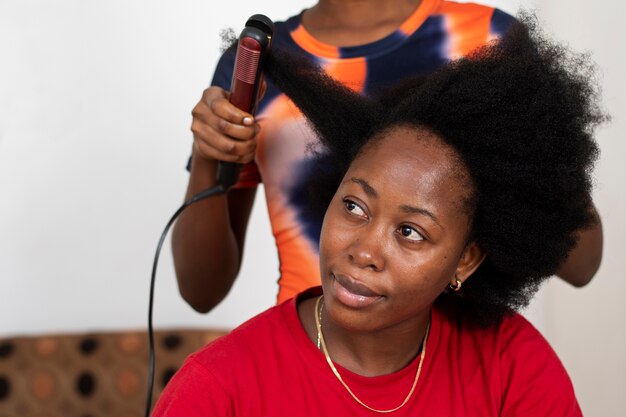 Femme styliste prenant soin des cheveux afro de son client