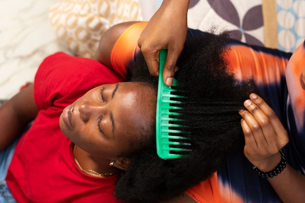 Femme styliste prenant soin des cheveux afro de son client