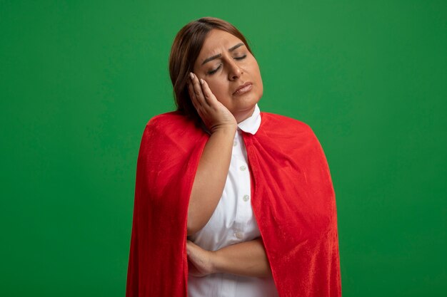 Femme de super-héros d'âge moyen avec les yeux fermés montrant le geste de sommeil isolé sur fond vert