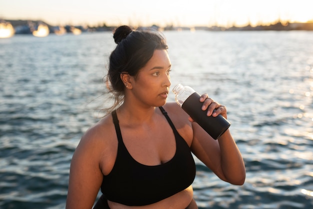 Femme en surpoids s'hydrater avec de l'eau après avoir fait de l'exercice à l'extérieur