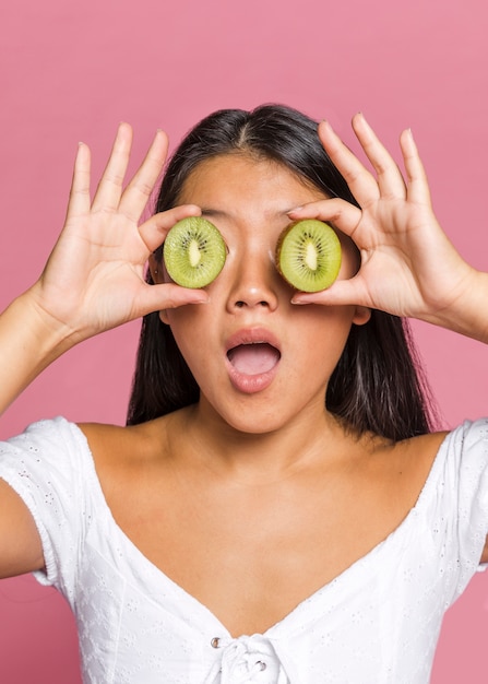 Femme surprise couvrant ses yeux avec du kiwi