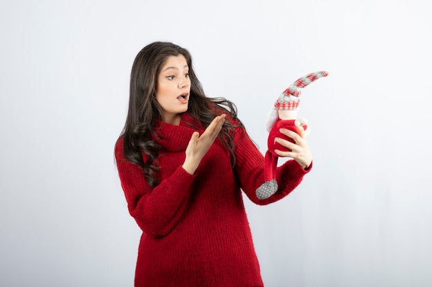 Femme surprise montrant une peluche du Père Noël..