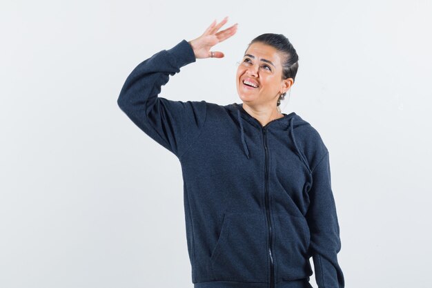 Femme en sweat à capuche montrant le geste de salut et à la vue de face, heureux.