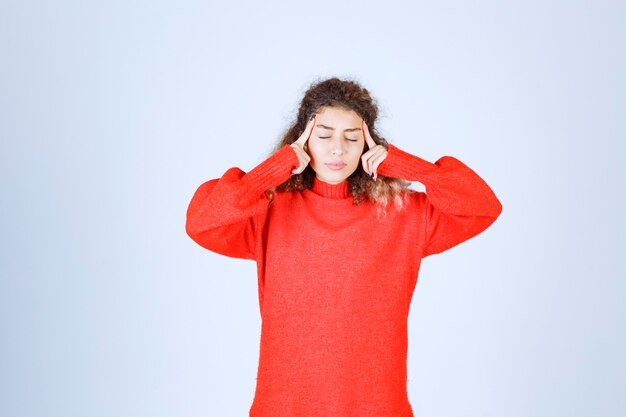 la femme en sweat-shirt rouge a l'air confuse et réfléchie.