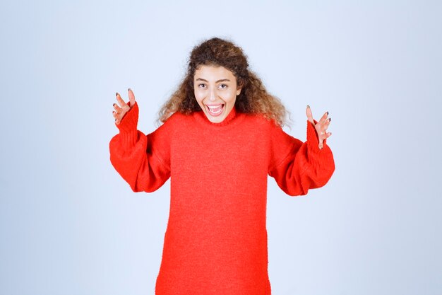 femme en sweat-shirt rouge donnant des poses souriantes et séduisantes.