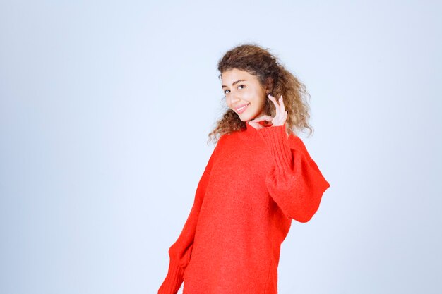 femme en sweat-shirt rouge montrant un signe de plaisir.