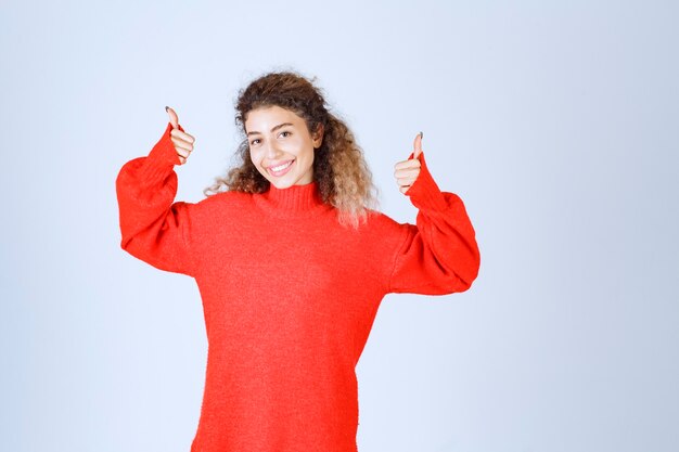 femme en sweat-shirt rouge montrant un signe de plaisir.