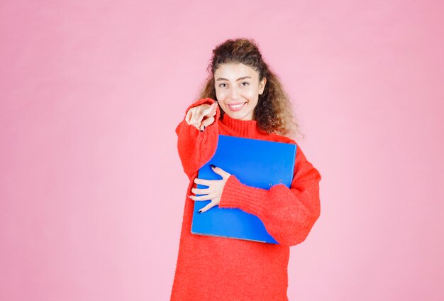 femme en sweat-shirt rouge pointant quelqu'un vers l'avant.