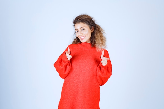 femme en sweat-shirt rouge pointant quelqu'un vers l'avant.