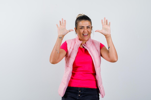 Femme en t-shirt, gilet montrant les paumes vides et l'air heureux