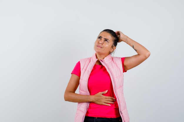 Femme en t-shirt, gilet se grattant la tête et à la réflexion