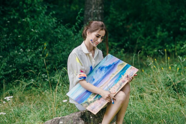 Femme avec t-shirt de peinture tachée regardant une image qui est dans sa main