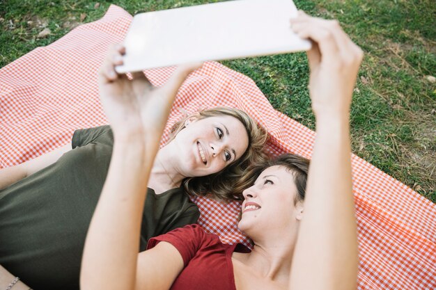 Femme avec tablette allongée sur une couverture